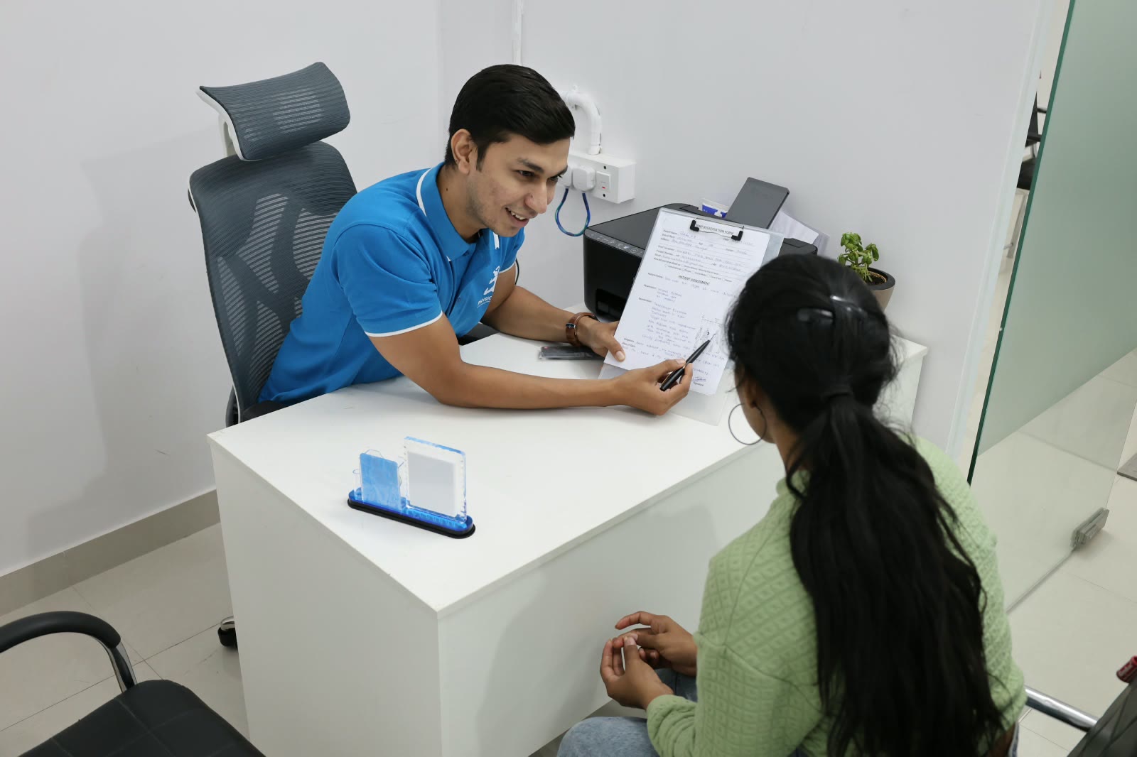 Dr. Tejas Lathiya walking a patient through her assessment findings at PhysioShine